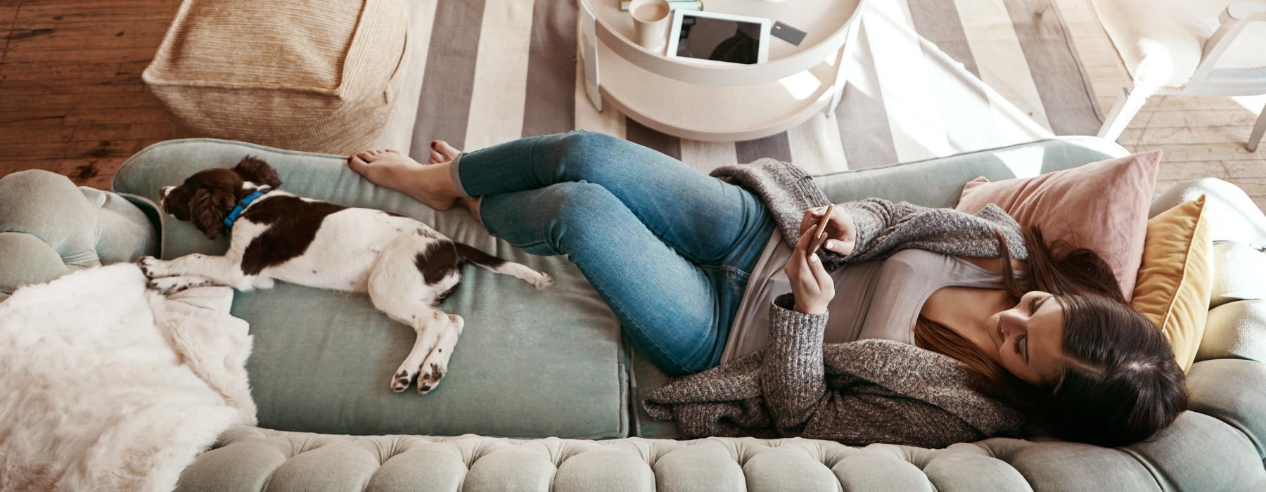 a person lying on a couch with a dog