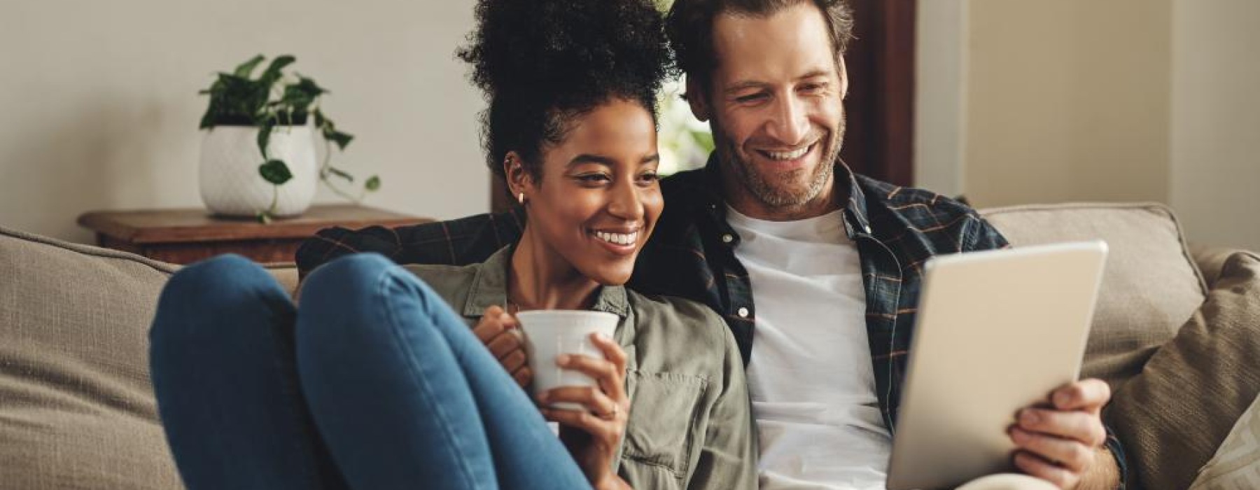 a man and a woman sitting on a couch looking at a laptop